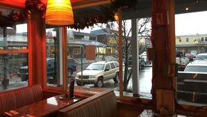 Ein Restaurant mit Blick auf die Straße, das ein großes Fenster, eine Sitzgruppe und eine Hängelampe zeigt.