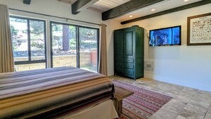 Une chambre à coucher avec un lit, une télévision, une armoire et une grande fenêtre.