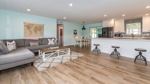 A modern living room with a grey sofa, wooden coffee table, and a world map on the wall. - Sunshine Stay, Central Fort Myers Gated Yard (Fort Myers)