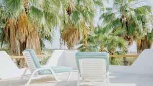 A beachside lounge with white lounge chairs and a view of palm trees. - Villa Gardenia - Oceanfront House Mango (Todos Santos)