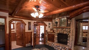 A cozy cabin interior with a stone fireplace, wooden beams, and a ceiling fan. - Rustic and Charming one Bedroom cabin. Upgraded pontoon! (Hayward)