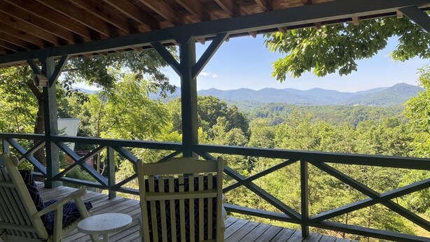 Une terrasse en bois offrant une vue sur une chaîne de montagnes boisées.