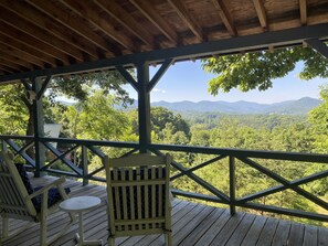 Une terrasse en bois offrant une vue sur une chaîne de montagnes boisées.