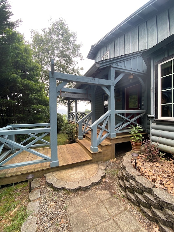 A wooden deck with a metal railing leading to a cabin entrance.