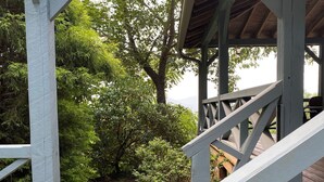 Une terrasse en bois avec une pancarte indiquant « Bienvenue dans notre chalet » et une vue sur un jardin luxuriant et des arbres.
