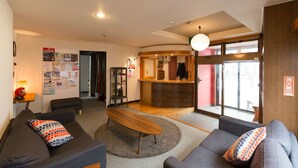 En moderne stue med sofa, sofabord og et receptionsområde i baggrunden.