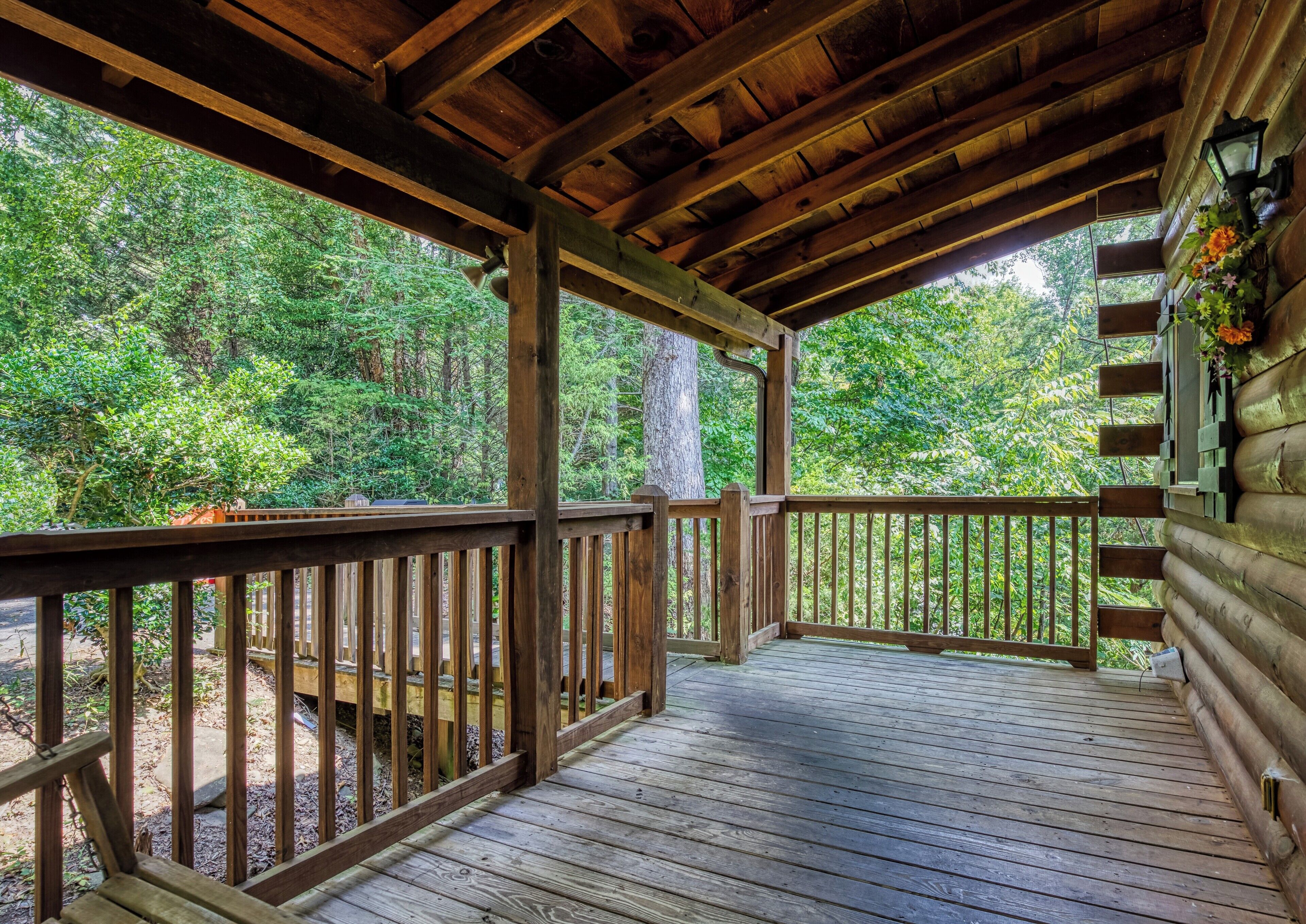 A wooden deck with railings, surrounded by lush greenery.