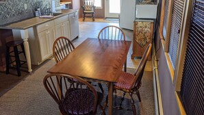 Una cocina compacta con zona de comedor, que incluye una mesa y sillas de madera, una pequeña isla con lavamanos y armarios sobre la encimera.