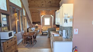 Cocina compacta con comedor, techo de madera y extintor en la pared.