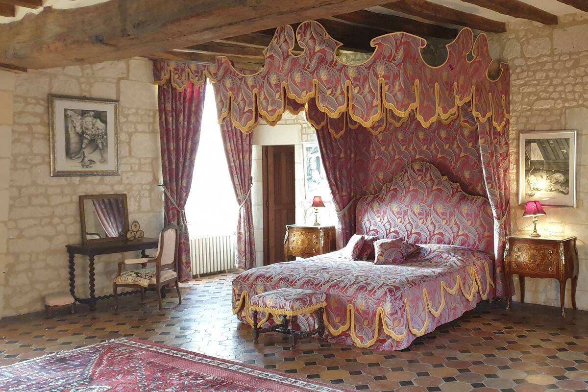 Une chambre à coucher avec un lit à baldaquin, des murs en pierre et un sol à carreaux.