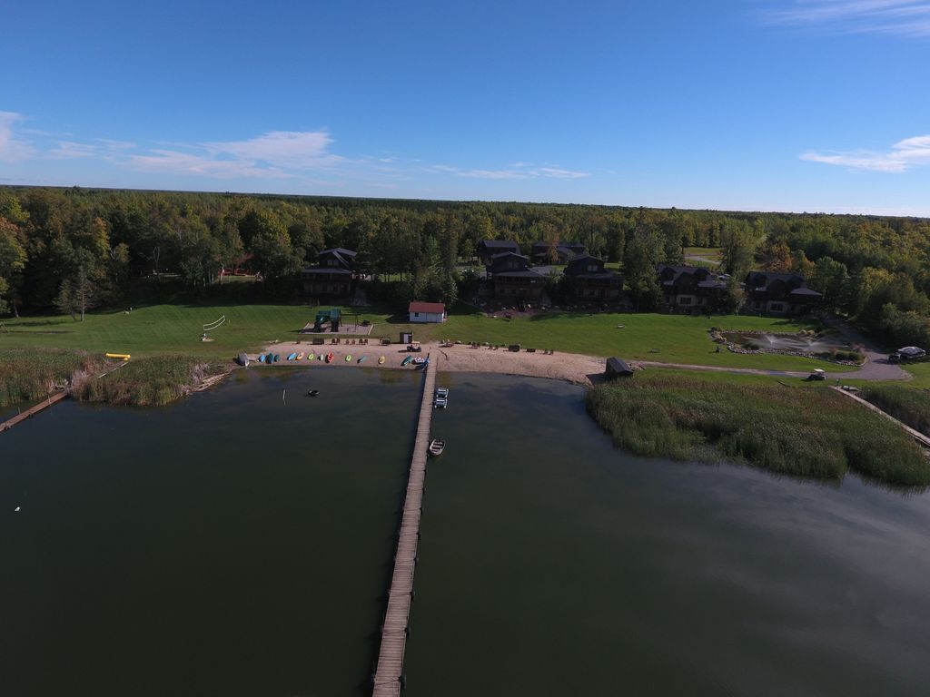 A lakeside property with a dock, a small building, and a forested background.