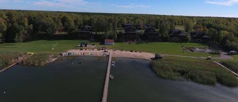 A lakeside property with a dock, a small building, and a forested background.