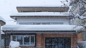 Um edifício de dois andares com telhado coberto de neve e janelas.