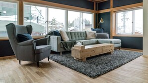 Uma sala de estar moderna com uma poltrona cinza, um sofá cinza e uma mesa de centro de madeira.