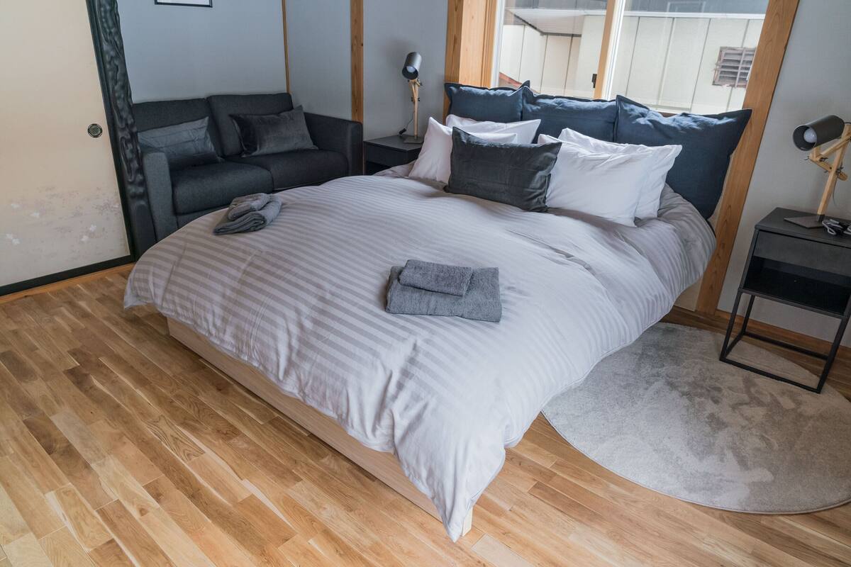 Un dormitorio con una cama grande, un sofá, una mesita de noche y un espejo.