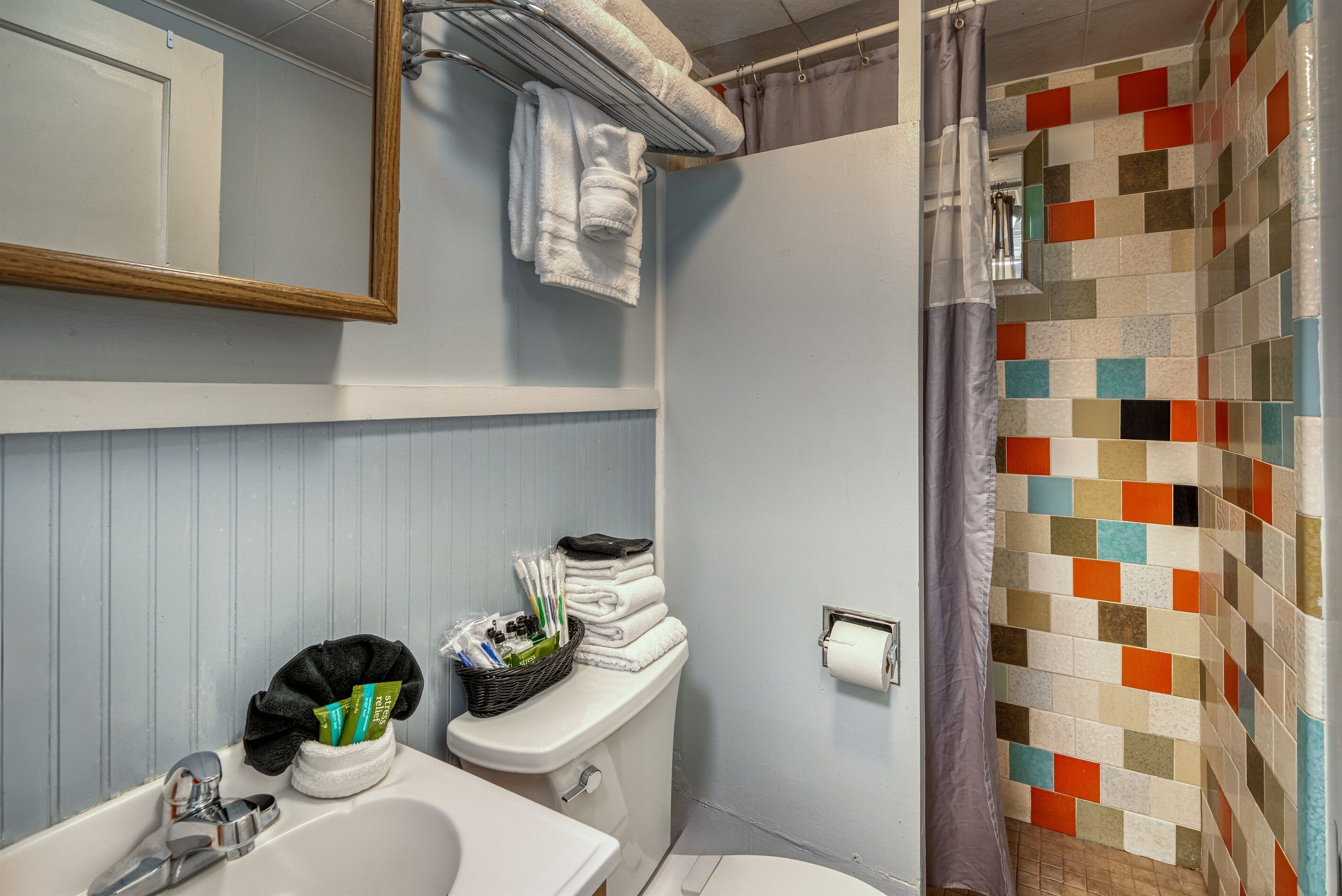 Une salle de bain équipée d’un lavabo, de toilettes et d’une douche. On y trouve des serviettes et des articles de toilette sur le lavabo et près des toilettes.