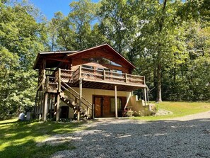 A wooden cabin with a balcony and a staircase leading to the entrance.