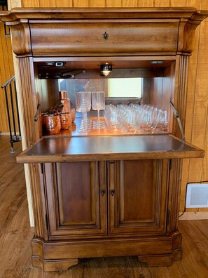 A wooden bar area with copper mugs, glasses, and a small bottle. - Pet friendly, hot tub, close to Hocking Hills! (McArthur)