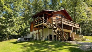 A wooden cabin with a balcony, surrounded by trees. - Pet friendly, hot tub, close to Hocking Hills! (McArthur)