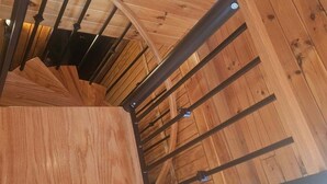 A wooden staircase with a metal handrail, leading to a room with a sloped ceiling and wooden walls. - Pet friendly, hot tub, close to Hocking Hills! (McArthur)