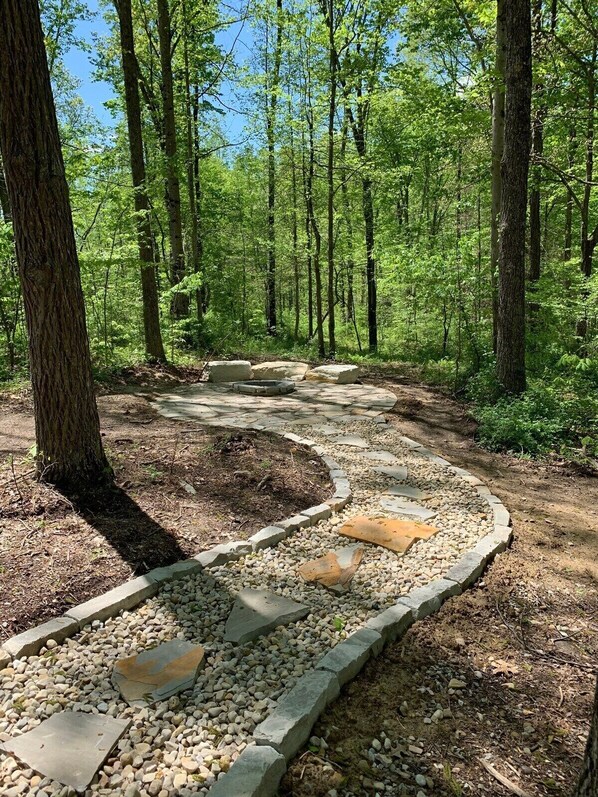 A forested area with a stone pathway and seating area.