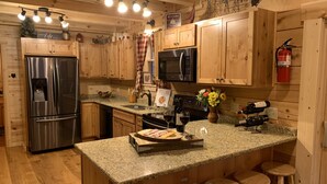 Una cocina moderna con armarios de madera, electrodomésticos de acero inoxidable y encimeras de granito, además de taburetes de bar.
