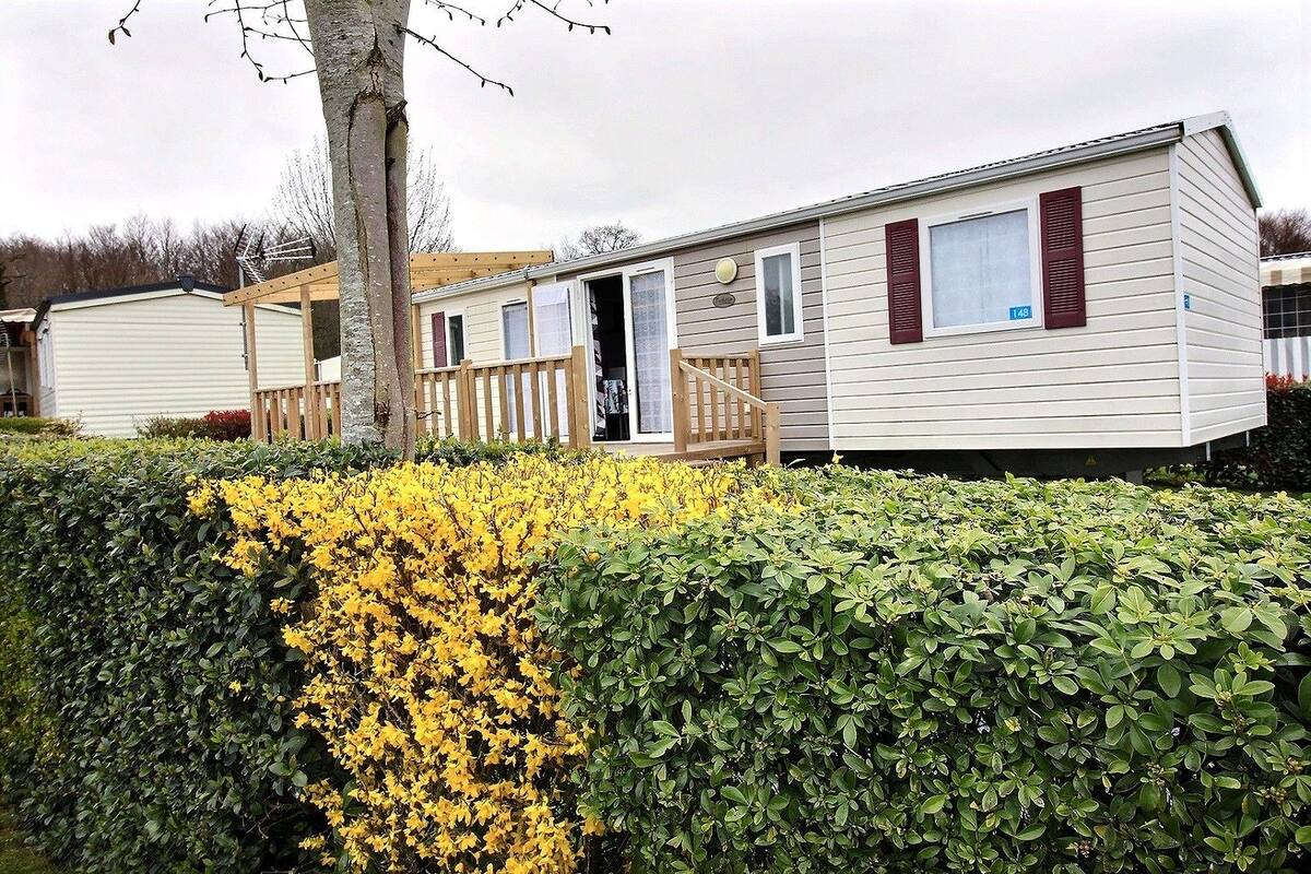 A mobile home with a wooden deck and a window with a number '148' on it.