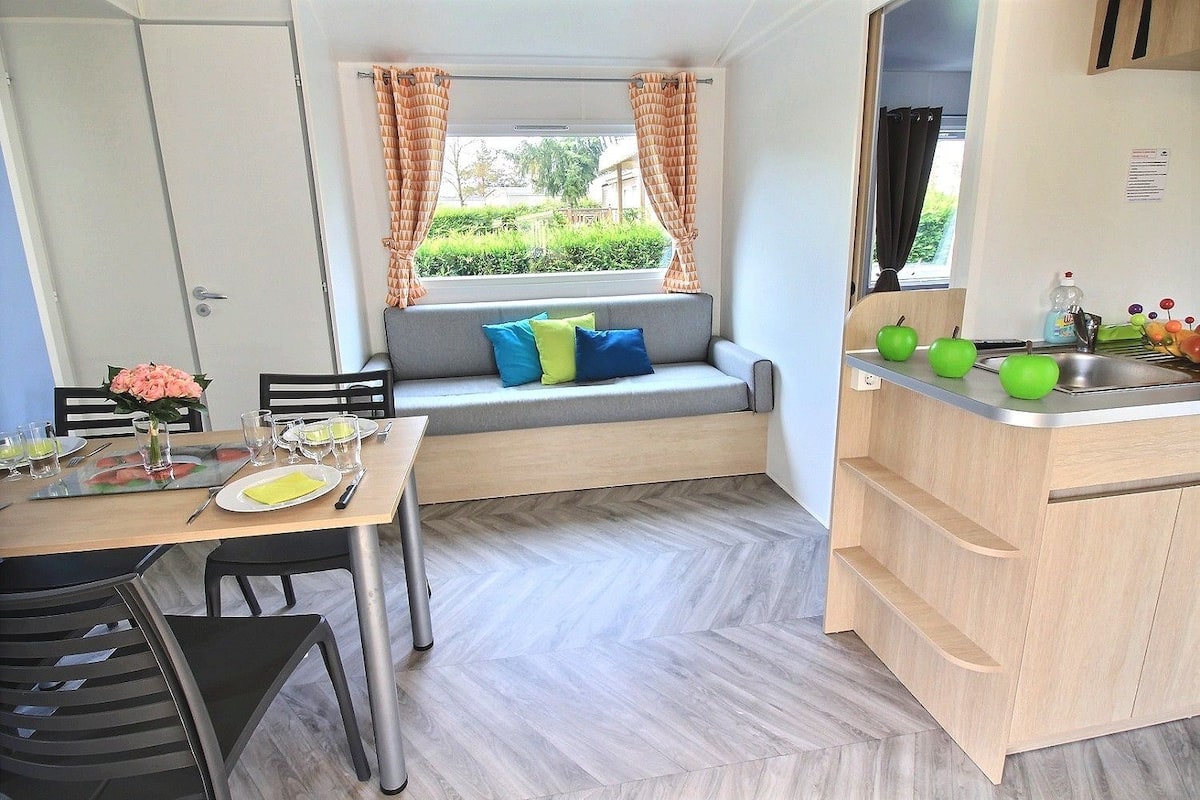 A compact kitchen with a dining area, a built-in bench, and a window with curtains.