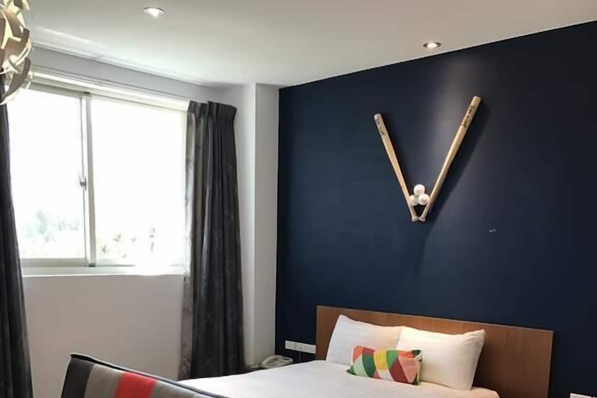A modern bedroom with a bed, a sofa, and a decorative wall piece.