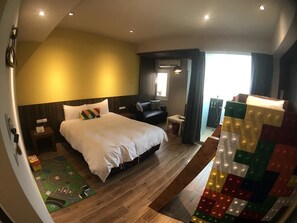 A hotel room with a large bed, a small seating area, and a view of the outdoors. - Rainbow House (Yuchi)