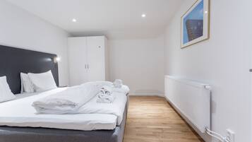 A modern hotel room with a neatly made bed, a large wardrobe, and a framed picture on the wall.
