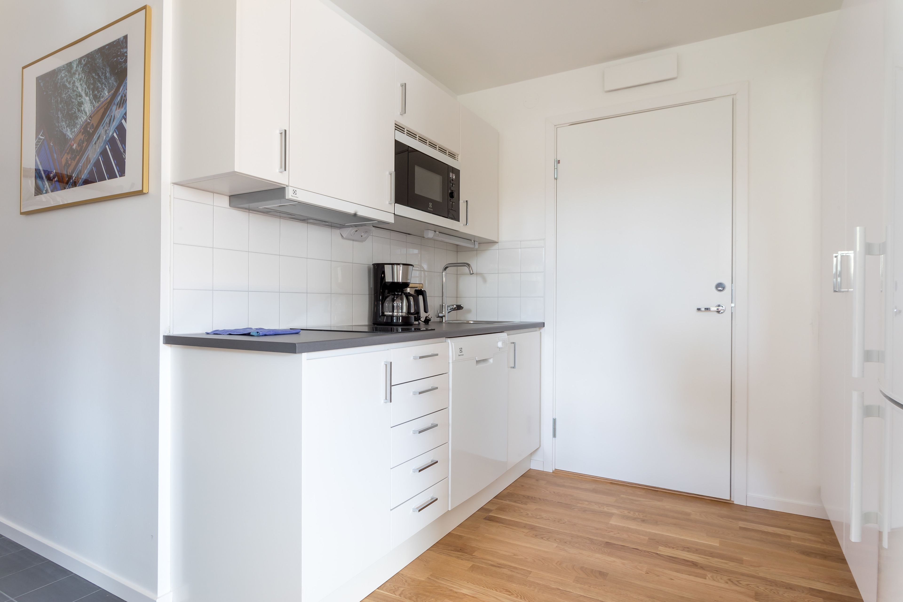 A modern kitchen with white cabinetry, a microwave, and a coffee maker.