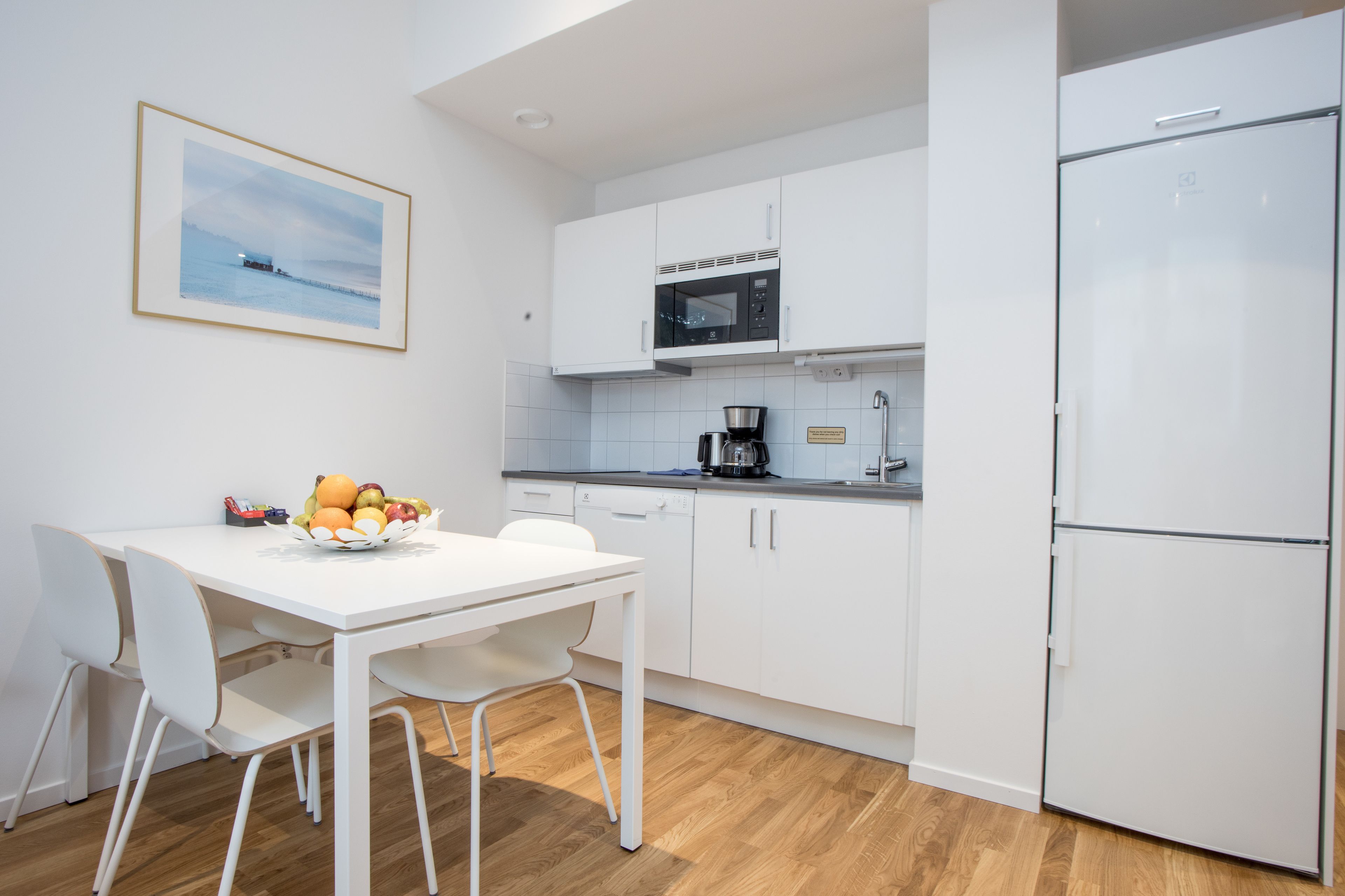 A modern kitchen with white cabinetry, a microwave, and a refrigerator.