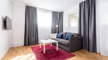 Un salon moderne avec un canapé gris, une table basse blanche et un tapis rouge.