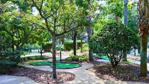 Um jardim bem cuidado com caminhos, árvores e um pequeno lago.
