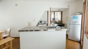 A modern kitchen with a central island, stainless steel appliances, and wooden flooring. - Nozawa Cottage (Nozawaonsen)