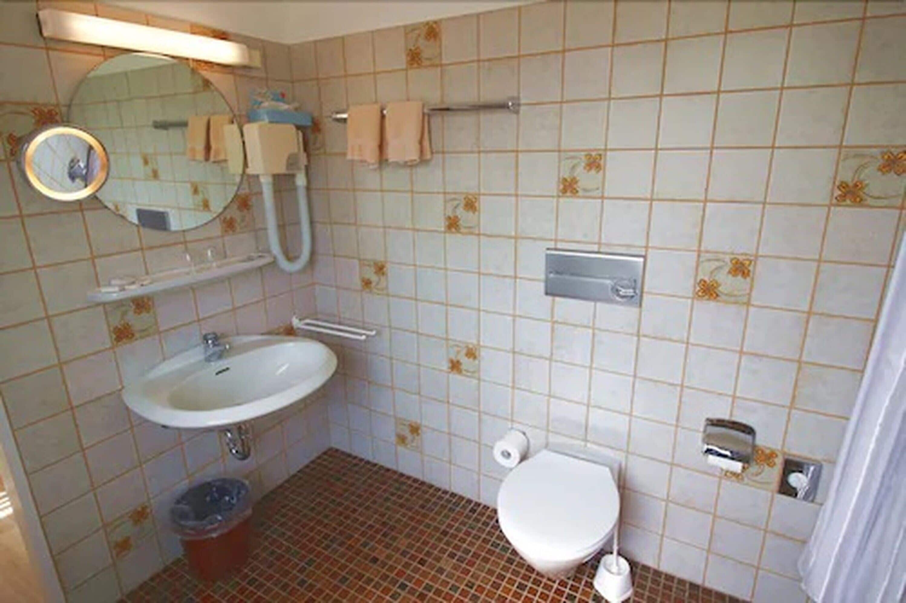 Un baño con lavamanos, inodoro y espejo.