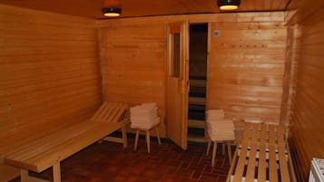 A wooden sauna room with benches and towels.