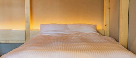 A single bed with a wooden headboard and a plain wall behind it.