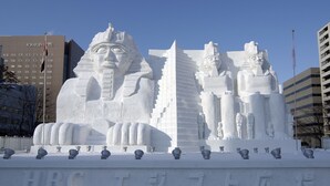Una gran escultura de nieve con faraones egipcios y pirámides frente a un hotel.