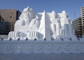Una gran escultura de nieve con faraones egipcios y pirámides frente a un hotel.