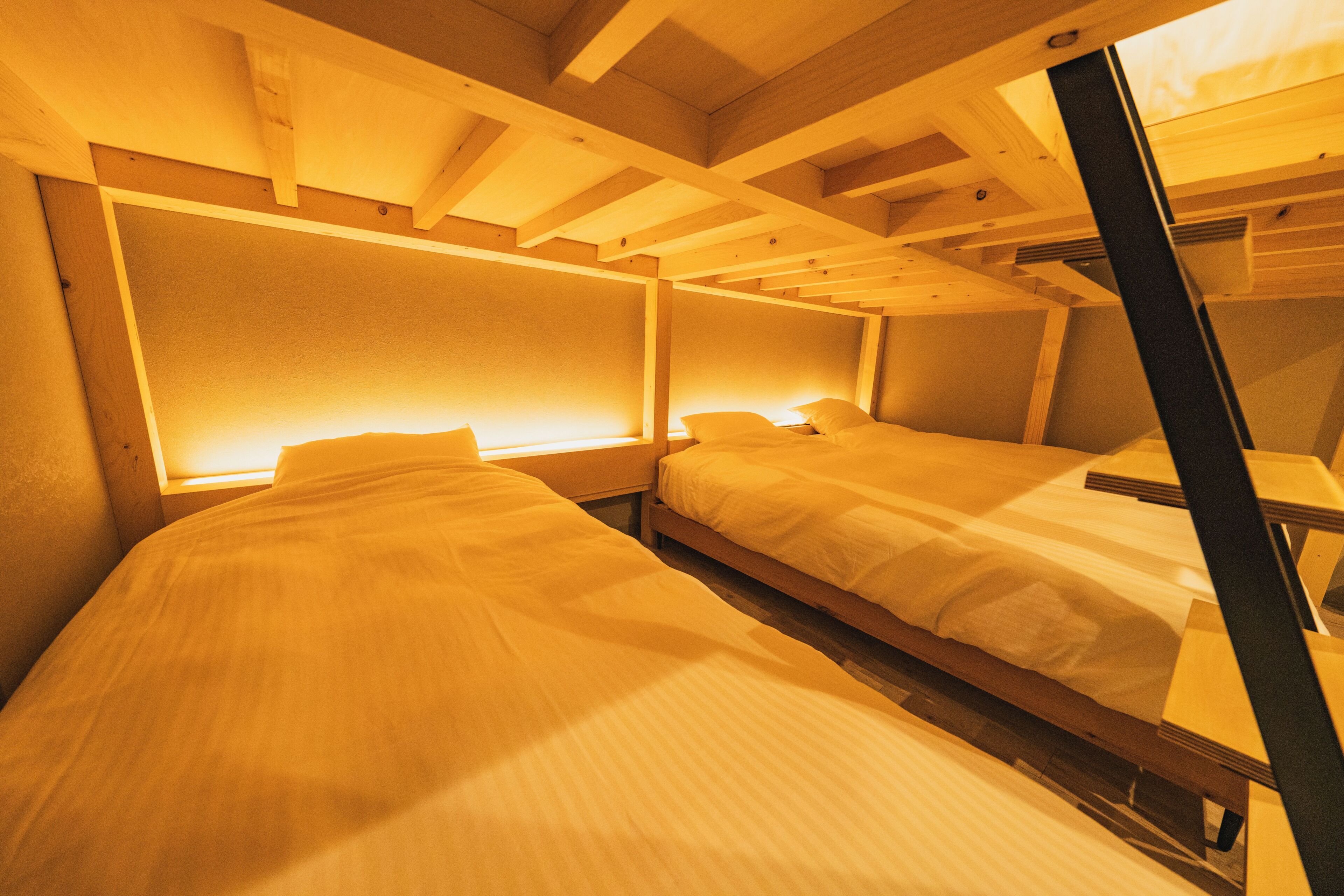 A room with two beds, wooden beams on the ceiling, and a window.