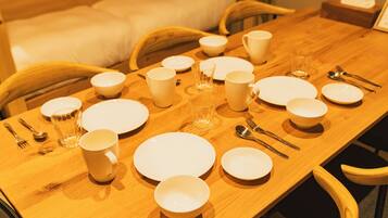 A dining table set with white plates, bowls, cups, and cutlery.