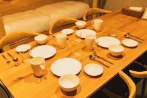 A dining table set with white plates, bowls, cups, and cutlery. - The Base Sapporo Susukino (Sapporo)