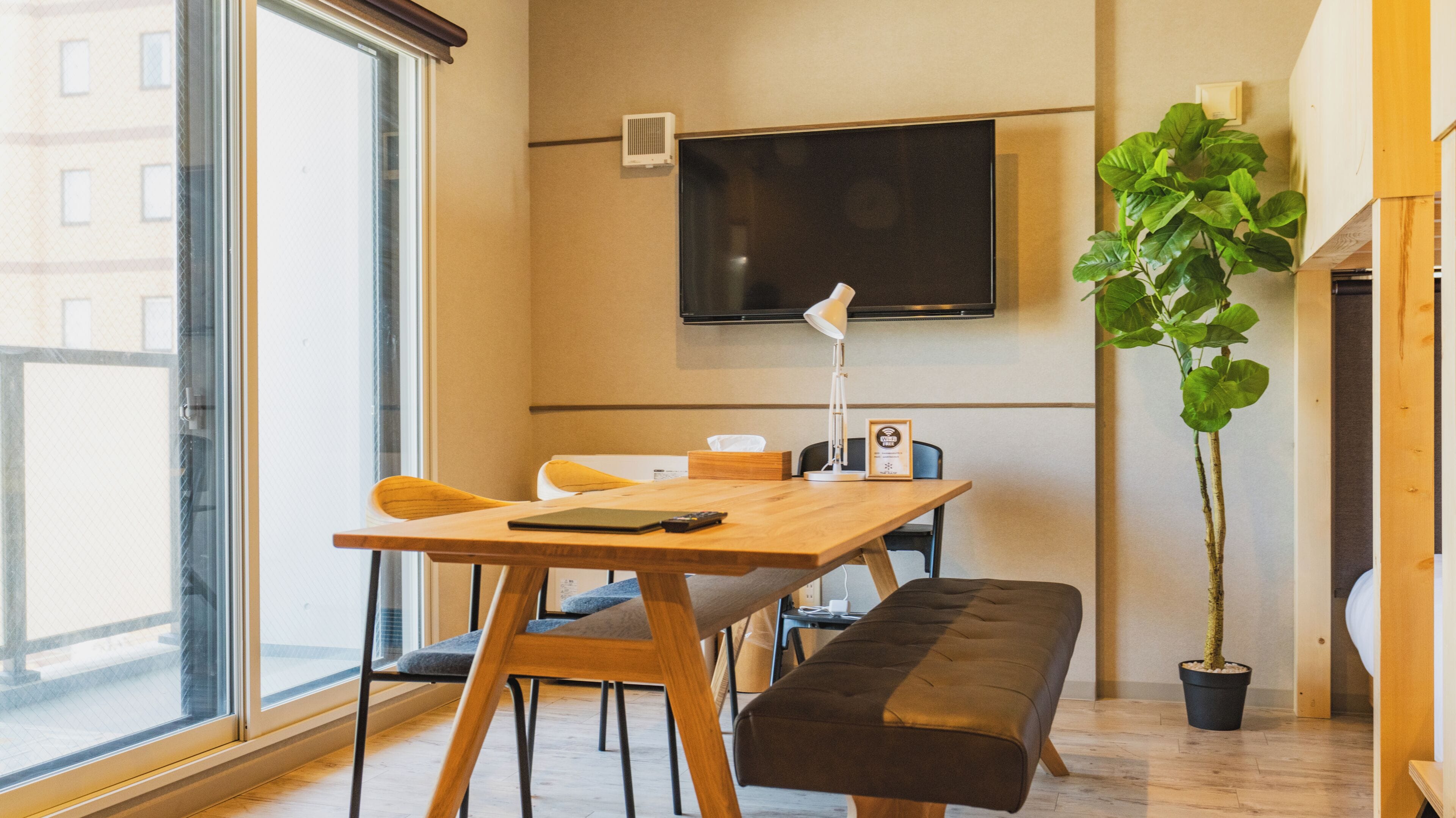 A modern room with a wooden table, bench, and a large potted plant.