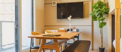 A modern room with a wooden table, bench, and a large potted plant.