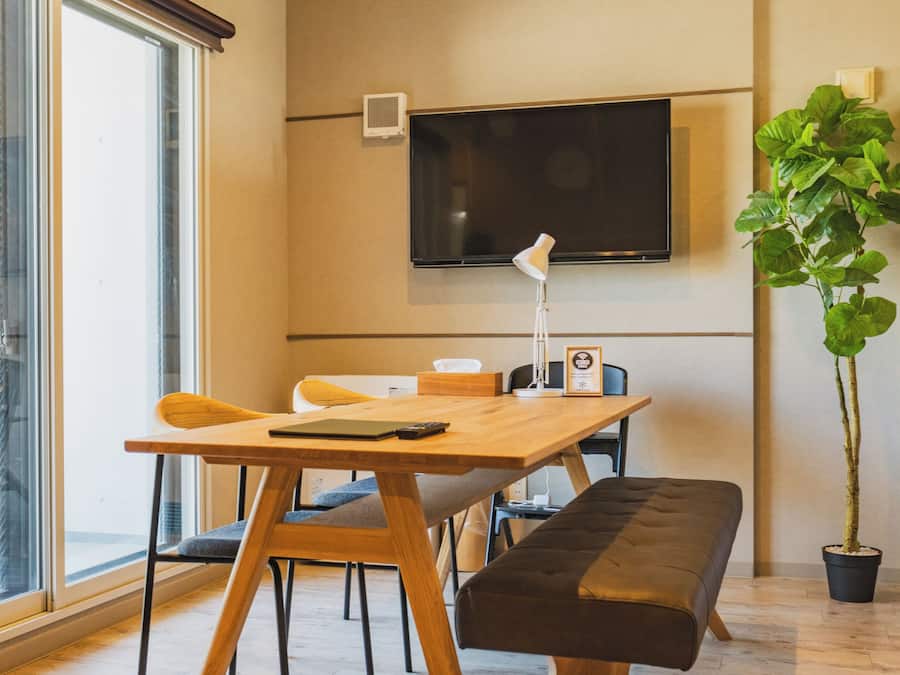 Una habitación moderna con una mesa de madera, un banco y una planta grande en maceta.
