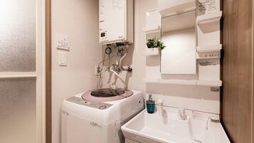 A bathroom with a built-in washing machine, a sink, and a mirror.