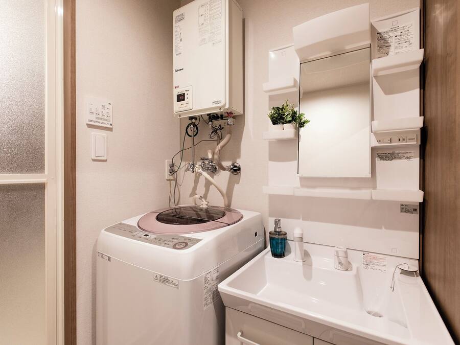 A bathroom with a built-in washing machine, a sink, and a mirror.