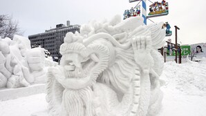 A snow sculpture of a dragon with intricate details, set against a backdrop of a building and a colorful sign. - The Base Sapporo Susukino (Sapporo)